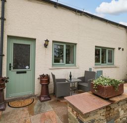 An outdoor seating area with a table and chairs at Yeat Stoup Cottage in Cockermouth