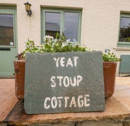 A sign indicating Yeat Stoup Cottage outside a building in Cockermouth