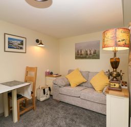 A snug room with a sofa and table at Yeat Stoup Cottage in Cockermouth