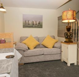 A living room with a sofa and staircase at Yeat Stoup Cottage Cockermouth
