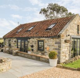 Stone cottage with tiled roof patio area and outdoor seating at Cowshed Normanby near Flyingthorpe