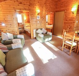 A wooden living room with green armchairs a sofa and a dining table at Goldcrest in Withern near Alford