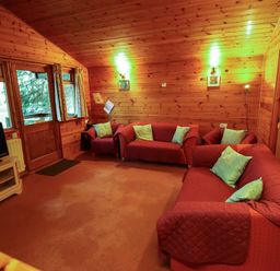 A living room with red sofas and light blue cushions in a wooden cabin at Partridge in Withern near Alford