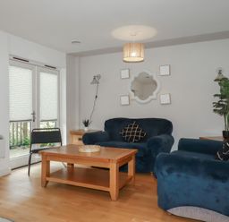 A living room with blue sofas wooden coffee table and plants at Treburgett in Porthtowan