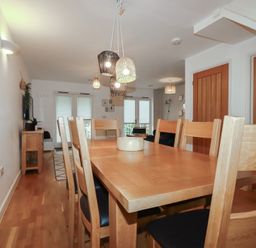 A dining room with a wooden table and chairs with pendant lights above at Treburgett in Porthtowan