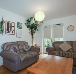 A sitting room with two striped sofas a wooden coffee table and framed pictures at Tregullan in Porthtowan