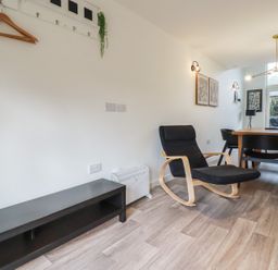 A dining area with a wooden table black chairs and a black armchair with wooden arms at Treveglos in Porthtowan