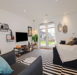 A living room with black and white striped rug sofas and a television at Treveglos in Porthtowan