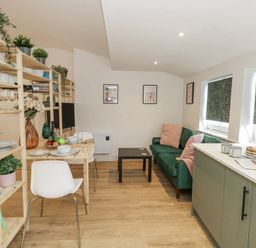 A living room with a dining area and kitchen appliances at Sea Pink Studio in Swanage