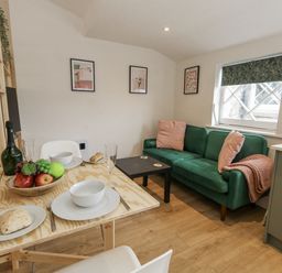 A living room with a sofa and dining table at Sea Pink Studio in Swanage