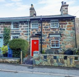A stone house with a red door and a bench outside at Llety in Beddgelert