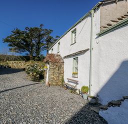 An outdoor view of a house with a bench and flowers at High Ickenthwaite Farmhouse in Ulverston