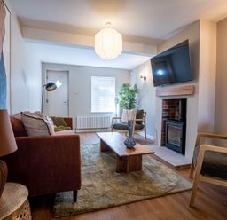 A living room with a sofa chairs coffee table rug and a fireplace with a mounted TV at Driftwood in Kessingland