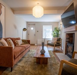 A living room with a sofa chairs coffee table fireplace and a wall mounted TV at Driftwood in Kessingland