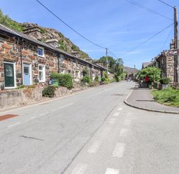 A street with stone houses and a road sign pointing to Ty Afon at Llys Emrys in Beddgelert