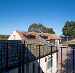 View of rooftops and a paved courtyard with trees and buildings in the background at The Cove in Kessingland