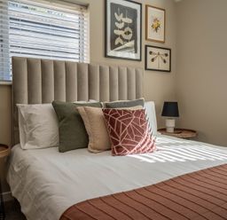 A bedroom with a bed with pillows and bedside tables with lamps at Dunes Cottage in Kessingland