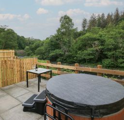 An outdoor area with a hot tub and table at Woof Luxury Family Pod in Keswick