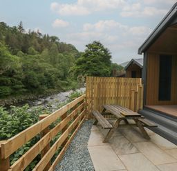 An outdoor area with a table and bench near a river at Lingy Luxury Family Pod in Keswick