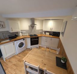 A kitchen with appliances and dining table at Hocking Cottage in St Marychurch