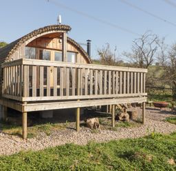A wooden cabin with a deck and outdoor seating area with fire pit at Cabanau Bach in Bedwas