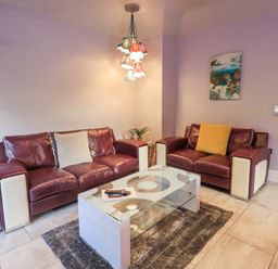 A living room with two leather sofas a glass coffee table and a hanging light at 1 The Old Coach House in Ambleside