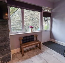 An entryway with a wooden bench and a wall-mounted television at 1 The Old Coach House in Ambleside