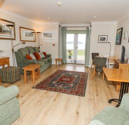 A living room with sofas tables and paintings on the walls at Carningli Suite near Newport