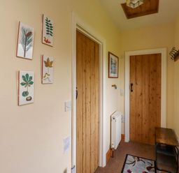 A hallway with wooden doors framed artwork a small bench a radiator and a rug at Folly View in Eglingham