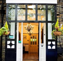 An entrance with black and white framed glass doors hanging plants and a chandelier inside at Fir Trees in Windermere