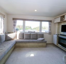 A living room with a corner sofa a television and a fireplace at 31A Foxburrow Hang Fritton near Belton Norfolk