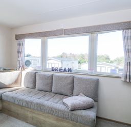 A corner sofa with cushions under windows with curtains and letters spelling dream at 31A Foxburrow Hang in Fritton near Belton Norfolk