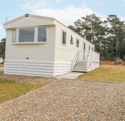 A beige mobile home with stairs and white railing located on a gravel and grass lot at 31A Foxburrow Hang in Fritton near Belton Norfolk