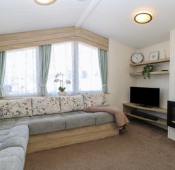 A living room with a sectional sofa and a television on shelves at 31B Foxburrow Hang in Fritton near Belton Norfolk