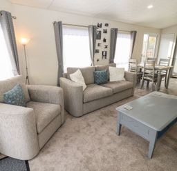 A living room with a sofa armchair coffee table and a dining table with chairs at Blossom Vale Lodge in Evesham