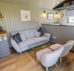 A small seating area with a sofa, two chairs, and a glass coffee table in a room at Buttercup in Ashby-cum-Fenby near Waltham