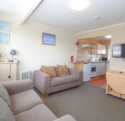 A living room with two sofas a wall mounted TV and an open kitchen area at Chalet 21 in Newport Norfolk