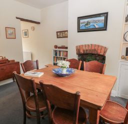 A dining room with wooden table and chairs a cupboard with plates and books at The Townhouse in Salisbury