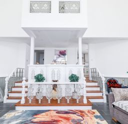 A living room with stairs and decorative railings leading to a dining area at Trelowth Chapel in Polgooth