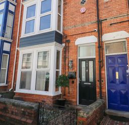A brick house facade with black door number 26 and blue door number 27 with bay windows Seaside House Weymouth