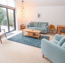 A living room with blue sofas a wooden coffee table and sliding glass doors at Chy Benyngoth in Hayle