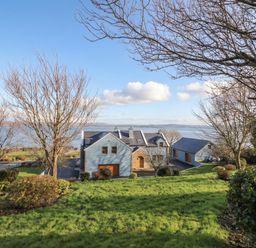 A view of a house with trees and a lake in the background at Ard Na Mara Drung near Quigley's Point, County Donegal