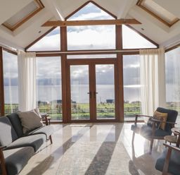 A conservatory with a sofa and armchairs overlooking a scenic view at Ard Na Mara in Drung near Quigley's Point, County Donegal