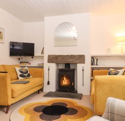 A living room with a fireplace and sofa at 2 New Mill Cottages in North Bovey