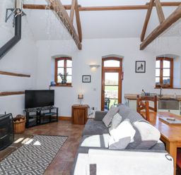 A living room with wood stove television sofa dining table and kitchen area at The Yarde Annexe Pen Elm near Taunton