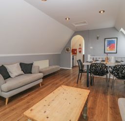 A living room with a sofa cushions wooden coffee table dining table and chairs at Valley Lodge 38 in St Ann's Chapel Cornwall