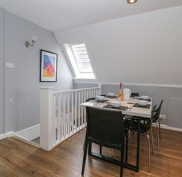 A dining area with a table set with bowls plates and utensils next to a staircase and a window at Valley Lodge 38 in St Ann's Chapel Cornwall
