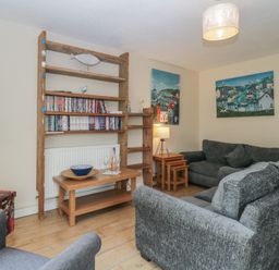 A living room with grey sofas wooden shelves and two paintings on the wall at 26 Manorcombe St Ann's Chapel Cornwall
