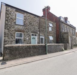 A street view of stone houses with a low stone wall and a lamppost in front at Colliers Cottage in Cinderford