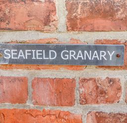 A metal sign with the text Seafield Granary mounted on a brick wall at Seafield Granary in Alnmouth
